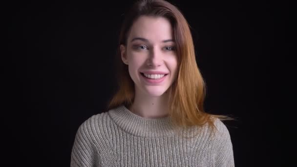 Portre portre genç güzel sevimli beyaz kızın saçlarını düzeltmesine ve ona boyun arkasında tutarak gülümseyen — Stok video