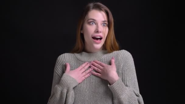 Closeup portrait of young beautiful caucasian female getting surprised and amused in front of the camera with background isolated on black — Stock Video