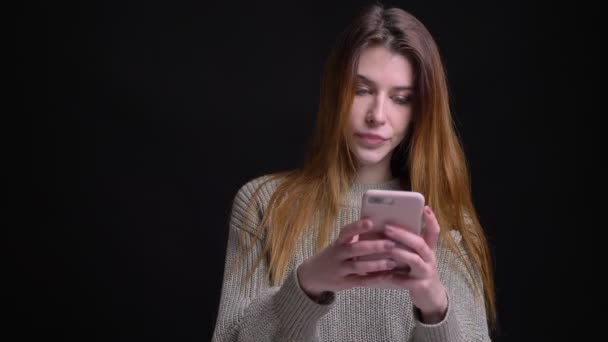 Nahaufnahme Porträt einer jungen schönen kaukasischen Frau, die das Telefon benutzt und vor der Kamera lächelt — Stockvideo