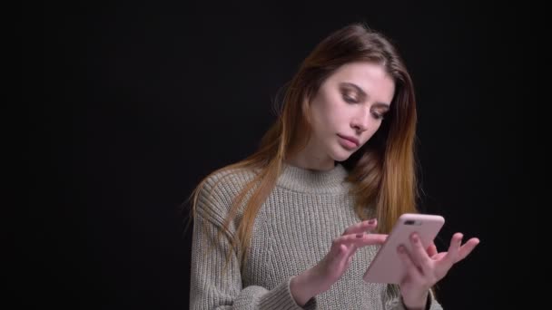 Nahaufnahme Porträt einer jungen hübschen kaukasischen Frau, die im Internet surft, dann in die Kamera schaut und glücklich lächelt — Stockvideo