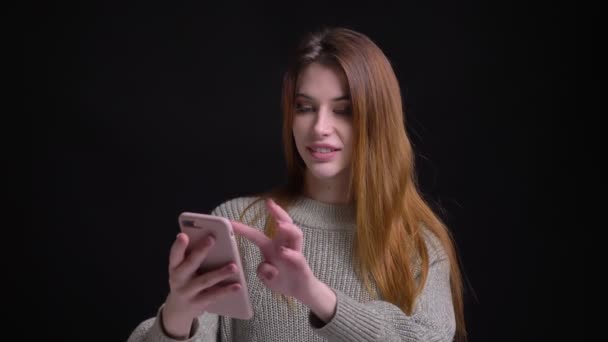 Närbild porträtt av unga ganska kaukasiska kvinnliga knacka på telefonen framför kameran — Stockvideo