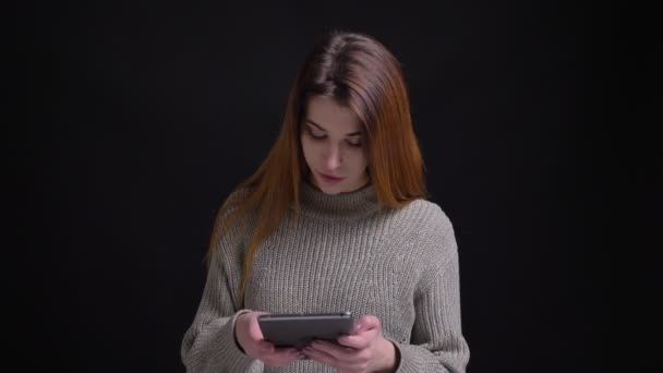 Крупный план портрет молодой привлекательной кавказской женщины с помощью планшета, затем смотреть в камеру и улыбаться — стоковое видео