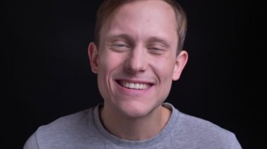 Genç çekici beyaz erkek gülen ve arka plan üzerinde siyah izole ile kameraya bakarken having fun closeup portresi