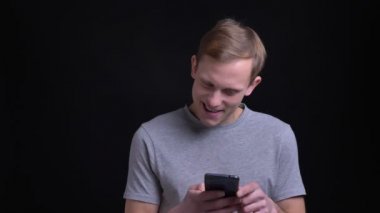 Telefonu kullanma ve kamera önünde gülümseyen genç çekici neşeli beyaz adam portresi portre
