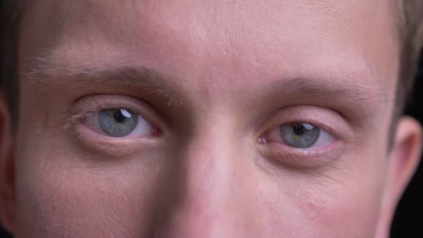 Closeup portret van de jonge knappe Kaukasische mannelijke gezicht met blauwe ogen direct kijken op camera met lachende gelaatsuitdrukking — Stockvideo