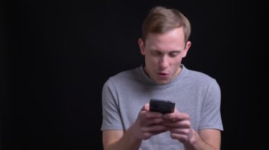 Telefonu kullanarak ve sonra kameraya bakıyor ve gülümsüyor gülüyor genç yakışıklı beyaz adam portresi portre