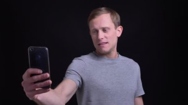 Portre portre genç çekici caucasain adam telefonda selfies alarak ve kamera önünde farklı yüz ifadeleri yapma