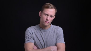 Portre portre genç yakışıklı beyaz adam ciddi ve kollarını göğüs üzerinde çarpı işareti olan ve gülümsemeye başladı