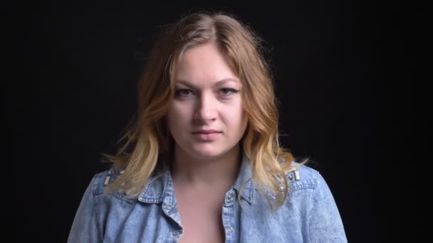 Closeup portret van volwassen mooie Kaukasische vrouw met kort blond haar kijken recht op de camera met achtergrond geïsoleerd op zwart — Stockvideo