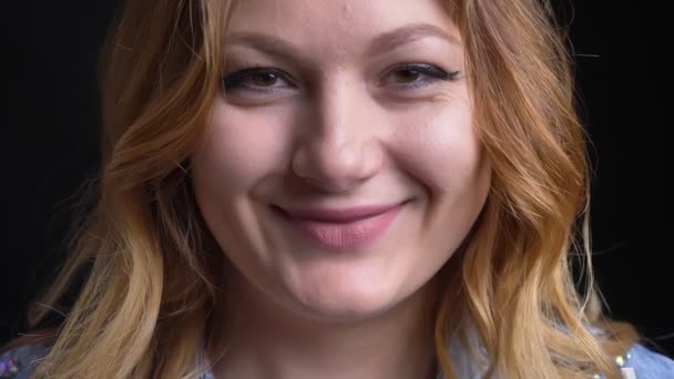 Крупный план портрет взрослой кавказской женщины, смеющейся и счастливой, глядя в камеру на фоне, изолированном на черном фоне — стоковое видео