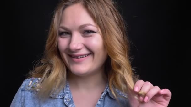 Retrato de close-up do adulto caucasiano feminino sorrindo flertando e brincando com o cabelo enquanto olha para a câmera — Vídeo de Stock