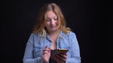 Portre portre yetişkin beyaz sarışın kadın kameraya bakarak ve mutlu bir şekilde gülerek telefonda yazmak
