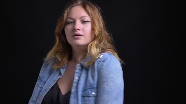 Nahaufnahme Porträt einer erwachsenen kaukasischen weiblichen Plus-Size-Model posiert vor der Kamera mit Hintergrund isoliert auf schwarz — Stockvideo