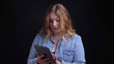 Kameraya bakarak ve arka plan üzerinde siyah izole ile gülümseyen tablet yetişkin beyaz kadın manifatura closeup portresi