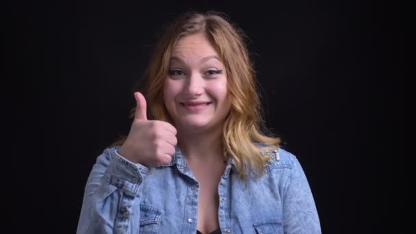 Closeup portret van volwassen Kaukasische vrouwelijke kijken camera glimlachen en duim opdagen — Stockvideo