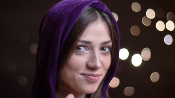 Closeup πορτρέτο του νέους καυκάσιος γυναίκα σε ένα hoodie seductively χαμογελώντας και κοιτάζοντας κατευθείαν στην κάμερα — Αρχείο Βίντεο