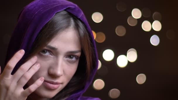 Närbild porträtt av unga ganska kaukasisk kvinna i en hoodie leende med charm och titta rakt på kameran — Stockvideo