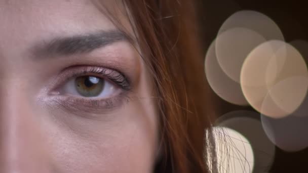 Primer plano retrato de media cara de joven hermosa mujer caucásica con ojo verde mirando directamente a la cámara — Vídeos de Stock