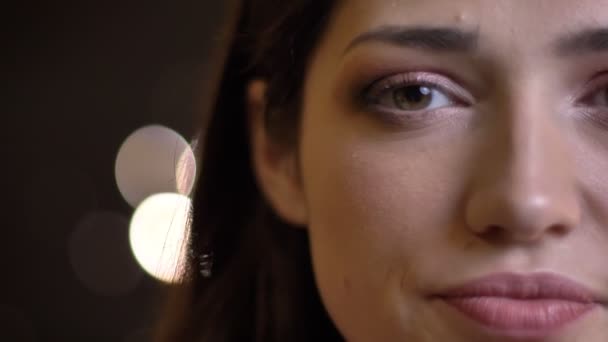 Closeup half-face portrait of young pretty caucasian female with green eyes looking straight at camera — Stock Video