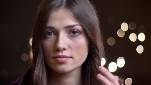 Closeup shoot of young charming caucasian female playing with her hair while looking at camera and turing to the side — Stock Video