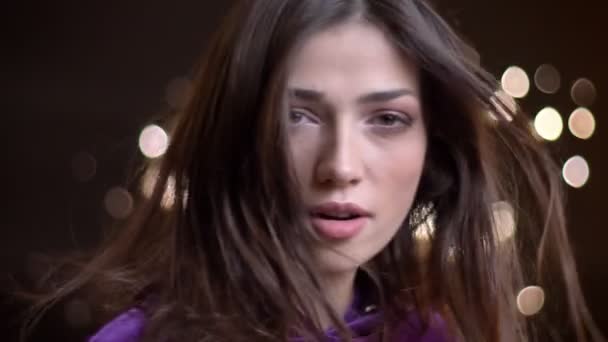 Closeup portrait of young stunning caucasian female turning to camera with her hair being fluttered by the windblow looking straight and smiling — Stock Video