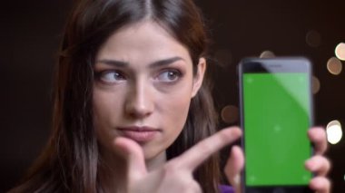 Yeşil ekranda işaret ve başparmak yukarıya el hareketi telefon tutarak genç oldukça beyaz kız closeup portresi