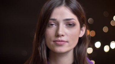 Rüya gibi bir gülümseme yapmak ve gece ile kameraya bakarken saçını sabitleme genç güzel beyaz kadın portresi closeup arka plan üzerinde ışıklar