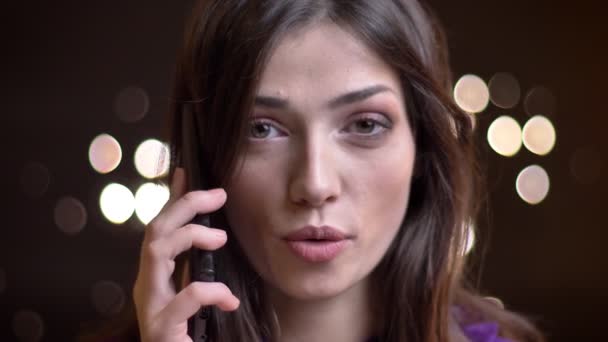 Closeup πορτρέτο του νεαρή όμορφη γυναίκα Καυκάσιος έχοντας μια περιστασιακή συνομιλία σχετικά με το τηλέφωνο και seductively βλέπουν φωτογραφική μηχανή — Αρχείο Βίντεο