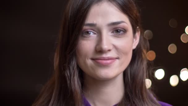 Detailní portrét mladé krásné jistý žena s úsměvem a při pohledu na fotoaparát s noční světla na pozadí — Stock video