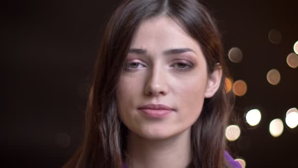Detailní portrét mladé krásné Kavkazský žena dělat zasněný úsměv a stanovení její vlasy při pohledu kamery s noční světla na pozadí — Stock video