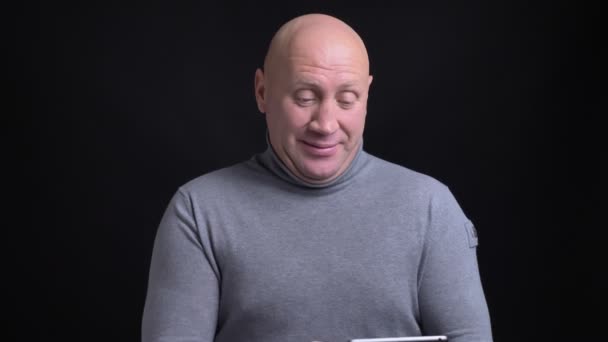 Retrato de close-up de homem caucasiano de meia-idade com uma chamada de vídeo emocional no tablet com fundo isolado em preto — Vídeo de Stock