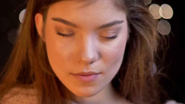 Close-up ritratto di giovane ragazza caucasica con gli occhi chiusi li apre felicemente su sfondo luci sfocate . — Video Stock