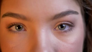 Yakın çekim göz-portresi beyaz kız kameraya cidden izlerken ışıkları arka plan bulanık.