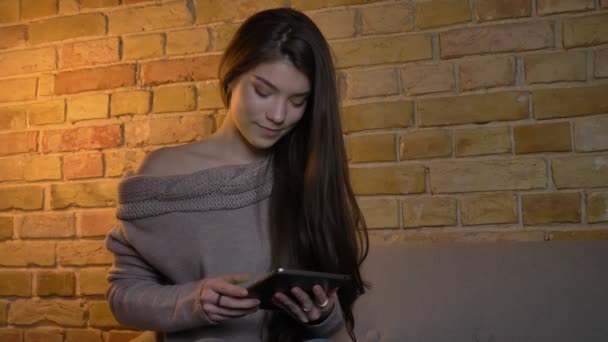 Potret close-up gadis muda Kaukasia menunjukkan layar hijau tablet ke kamera dengan gembira di latar belakang rumah yang nyaman . — Stok Video