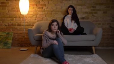 Oturma odasında ve tarassut belgili tanımlık Tv rahat ev atmosferi farklı duygular ile iki genç beyaz kız.