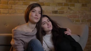 Yakın çekim portre tarassut belgili tanımlık Tv ve rahat ev zemin üzerine sarılma neşeli genç beyaz kızların.