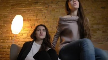 Birlikte katta oturan ve rahat ev ortamında olumlu eğlence ile film izlerken genç beyaz kız portresi.