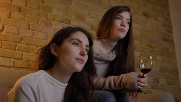 Yakın çekim portre neşeli genç beyaz kızlar oturup birlikte içki şarap ve rahat ev ortamında iletişim kurma. — Stok video