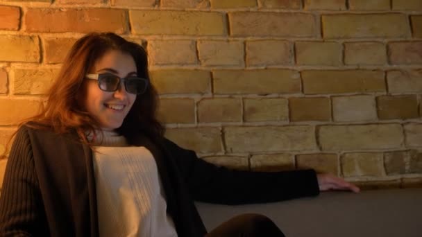 Kaukasische meisje met golvende haren zet uit haar 3D-bril in positieve amusement op gezellige huis achtergrond. — Stockvideo