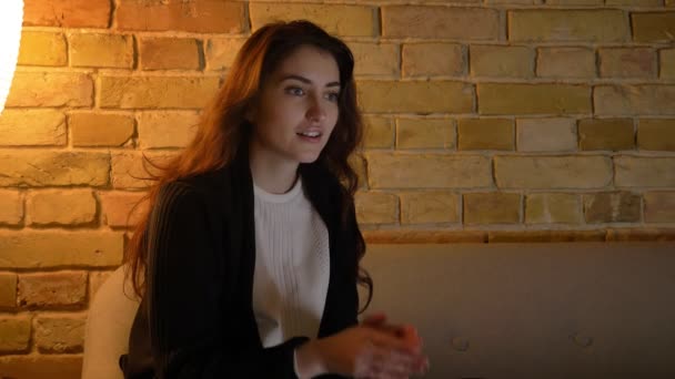 Молодая кавказская девушка с волнистыми волосами прячет лицо со страхом на уютном домашнем фоне. . — стоковое видео