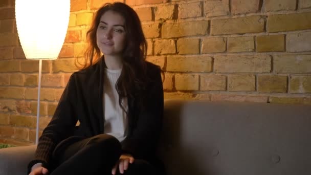 Porträt eines jungen kaukasischen Mädchens mit welligem Haar, das mit Interesse und Bewunderung Fernsehen auf gemütlichem heimischen Hintergrund schaut. — Stockvideo
