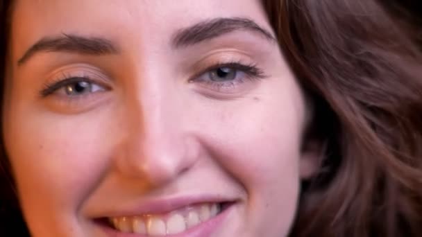 Close-up eye-portrait di profilo di giovane ragazza caucasica guardando gioiosamente in macchina fotografica su sfondo luci sfocate . — Video Stock