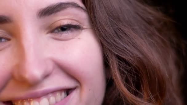 Primo piano mezzo ritratto di giovane ragazza caucasica che guarda sorridente in macchina fotografica su sfondo luci sfocate . — Video Stock