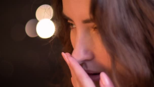 Retrato de cerca en el perfil de una joven caucásica bostezando sobre un fondo borroso de luces . — Vídeo de stock