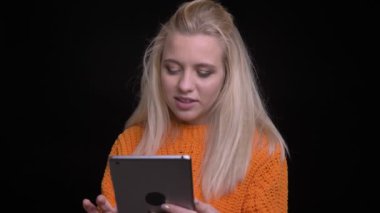 Closeup çekim genç oldukça beyaz kadın sonra kameraya bakıyor ve gülümsüyor tablete yazma