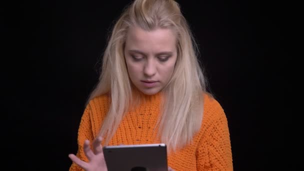 Close-up tiro de jovem muito caucasiano fêmea usando o tablet, em seguida, olhando para a câmera e sorrindo alegremente — Vídeo de Stock