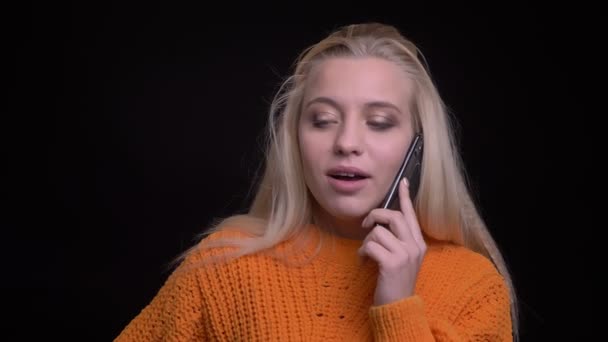 Close-up tiro de jovem muito caucasiano fêmea ter uma conversa casual no telefone na frente da câmera — Vídeo de Stock