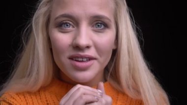 Closeup çekim heyecanlı ve mutlu bir şekilde gülümseyerek kameraya düz bakarken uzun sarı saçlı elde olan genç çekici beyaz kadın sürpriz