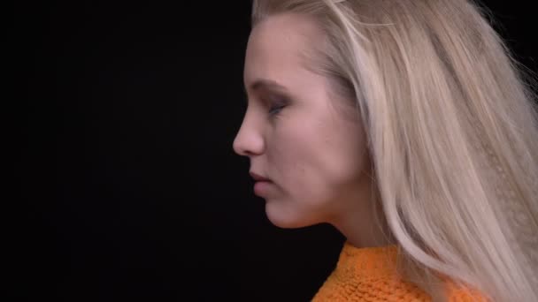 Retrato de close-up de jovem mulher branca atraente com cabelo loiro longo se voltando para a câmera e sorrindo alegremente — Vídeo de Stock