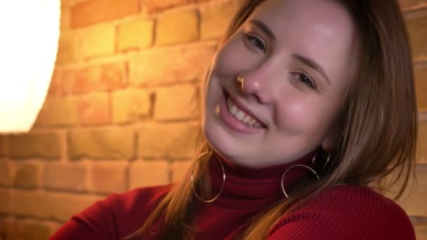 Zbliżenie strzelać młodym całkiem kaukaski kobiece kobieta marzy i uśmiechając się z radości w pomieszczeniu przytulny apartament — Wideo stockowe